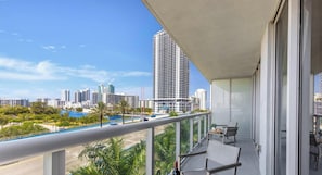 A balcony with a city view, a table with chairs, and a railing. - Amazing Apt + Private Balcony + Pool + Amenities (Hallandale Beach)