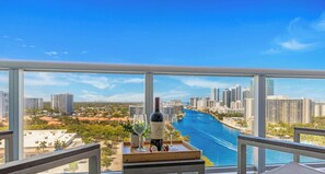 A balcony with a city view, a bottle of wine, and a tray with strawberries.