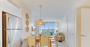 Una cocina moderna con un refrigerador de acero inoxidable, un comedor con mesa y sillas, y un ventanal que ofrece vistas.