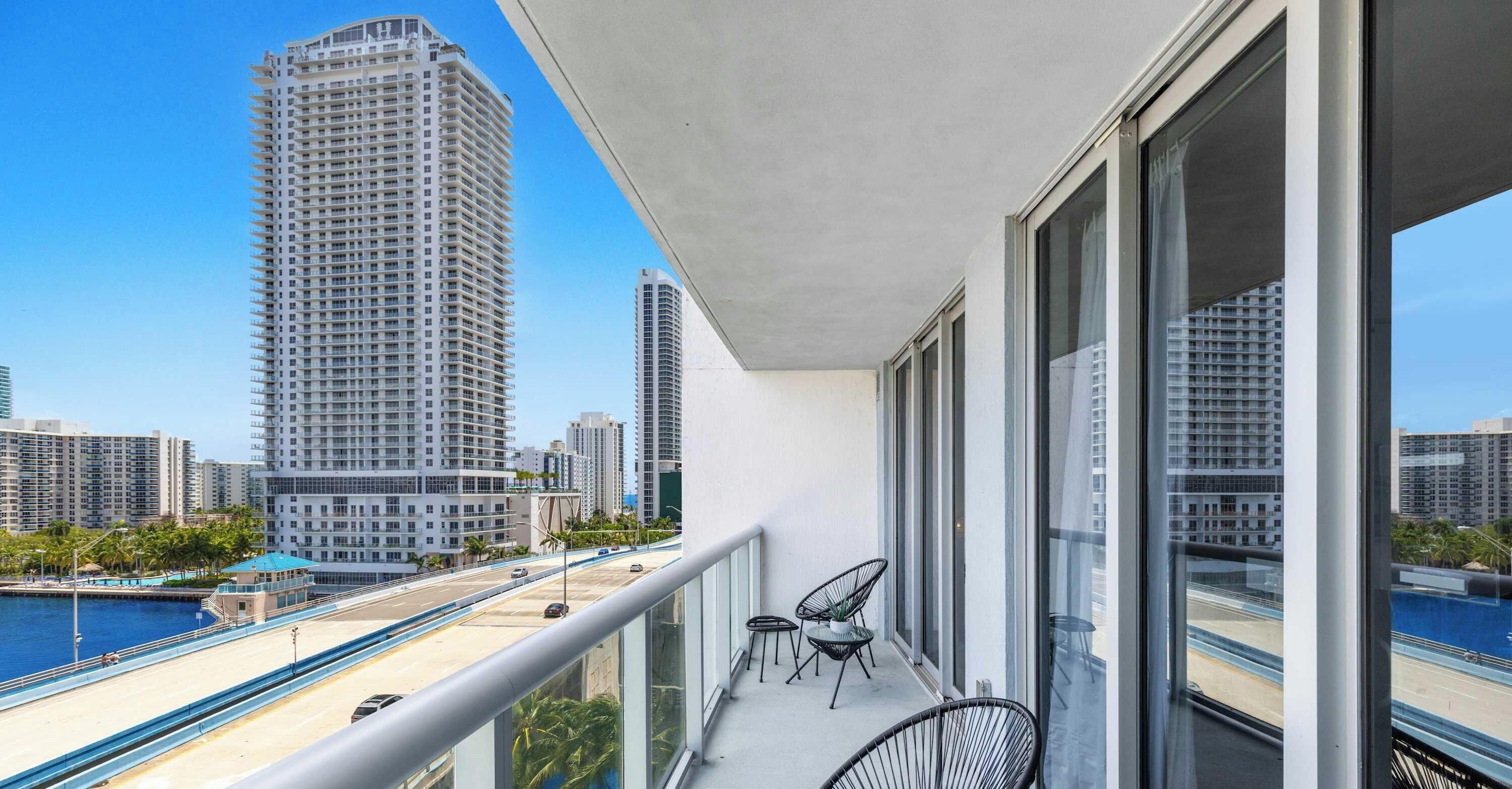 Ein Balkon mit Blick auf eine Skyline, darunter hohe Gebäude und ein Uferbereich.