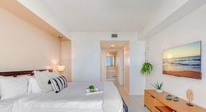 Una habitación de hotel moderna con una cama, una mesita de noche y un cuadro de una puesta de sol.