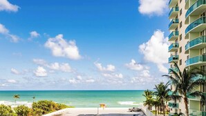 A beachfront hotel with a clear view of the ocean, a parking area, and a building with balconies. - Beautiful Apartment with Pool & Amenities (Hollywood)