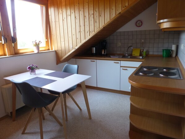 Une cuisine avec un plafond en bois, une table à manger avec des chaises, un évier et une cuisinière.
