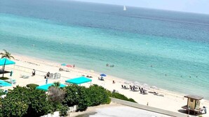 Una playa con agua turquesa cristalina, una torre de salvavidas y sombrillas.