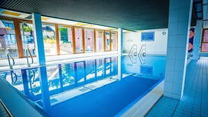 An indoor swimming pool with clear glass walls, a tiled floor, and a sign indicating the pool's name and rules. - Apartment 'Natur Tanken' with Mountain View, Shared Garden and Wi-Fi (Sasbachwalden)