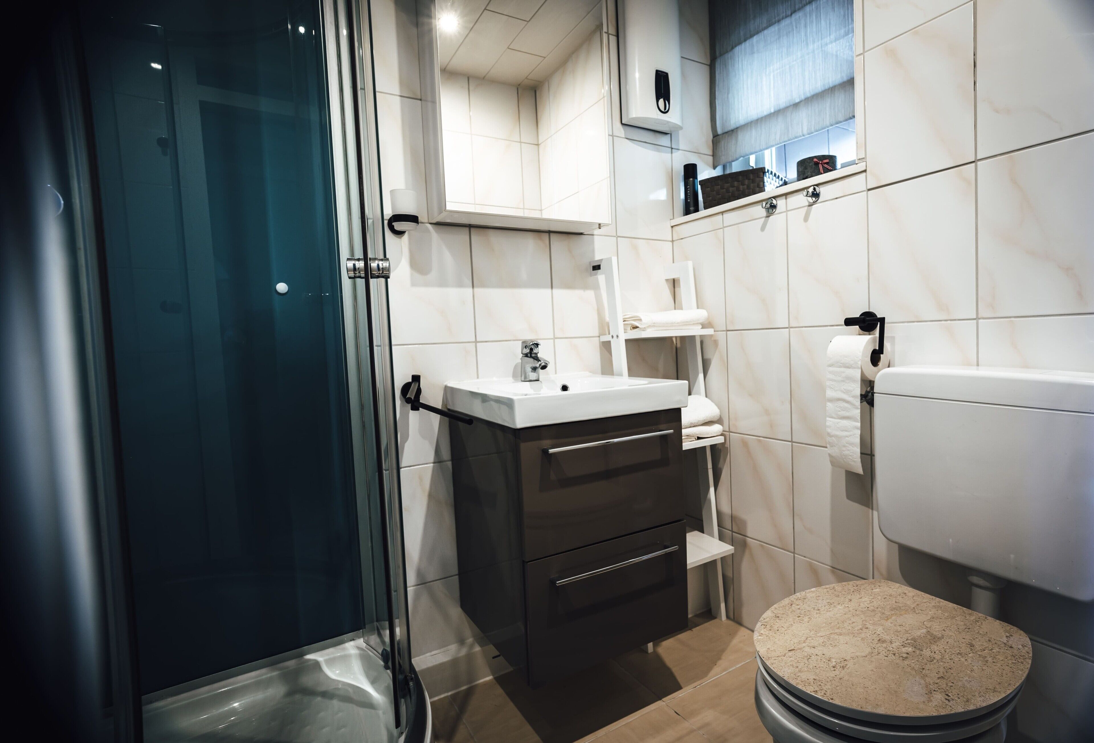 Une salle de bain moderne avec une douche à parois de verre, des toilettes blanches et un meuble-lavabo avec un miroir.