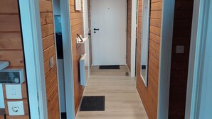 A hallway with wooden walls, a white door at the end, and a light fixture on the ceiling.