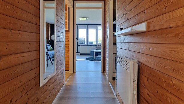 A wooden-paneled hallway with a mirror, a radiator, and a framed picture on the wall.
