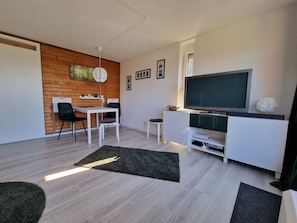Una sala moderna con comedor, un televisor de pantalla plana y una pared de acento de madera.