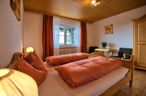 A room with a bed, a desk, a chair, a window with curtains, and a radiator.