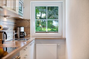 A modern kitchen with a window, a built-in microwave, a coffee maker, and a white radiator.