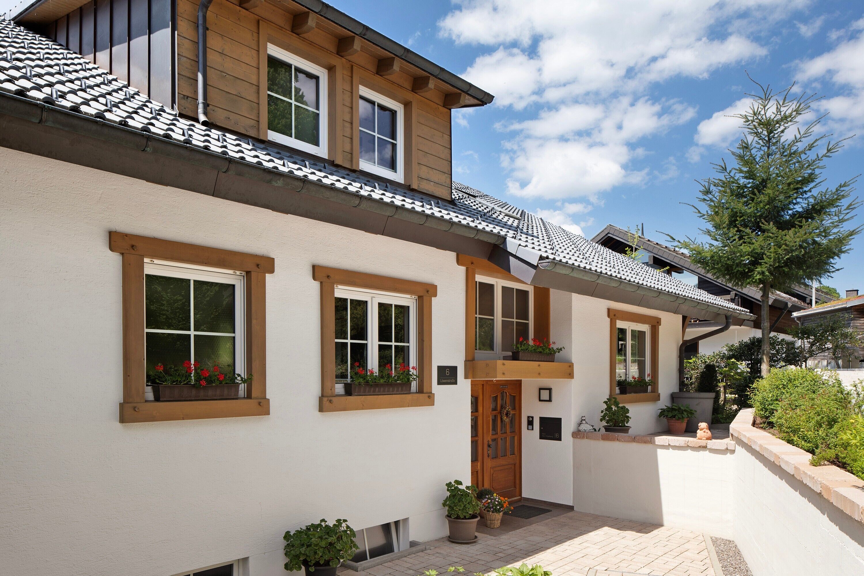 A two-story building with a tiled roof, wooden window frames, and potted plants.
