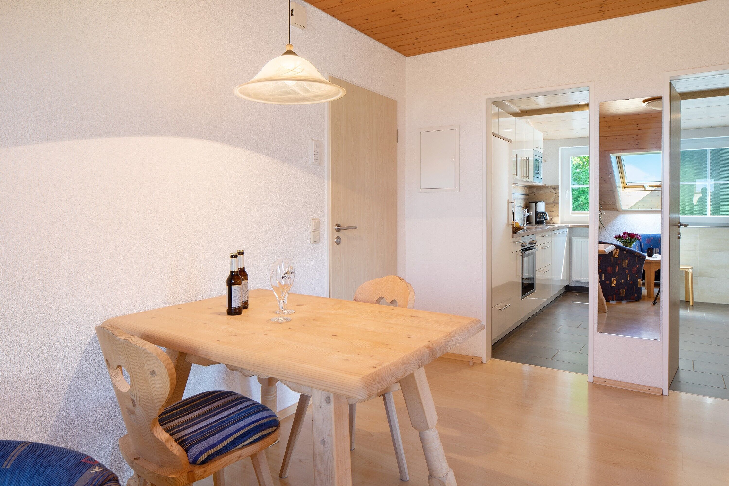 Un espace repas comprenant une table en bois, des chaises et un luminaire suspendu.