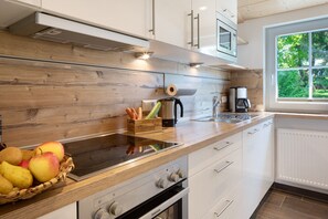 A modern kitchen with wooden cabinetry, a built-in oven, and a window with a view of greenery.