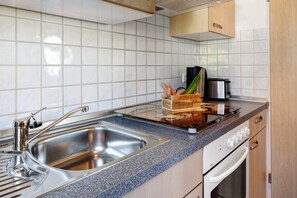 A kitchen with a stainless steel sink, a toaster, and a wooden fruit basket on the counter.