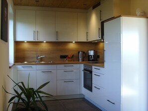 A modern kitchen with white cabinets, a stainless steel sink, and a built-in oven.