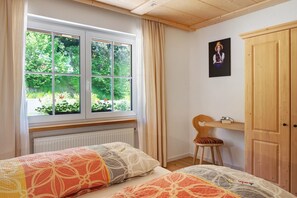 Une chambre avec deux lits, une fenêtre avec des rideaux, un bureau avec une chaise et une armoire.