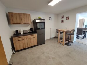 Una cuina funcional amb armaris de fusta, forn integrat, cafetera i zona de menjador amb taula i cadires.