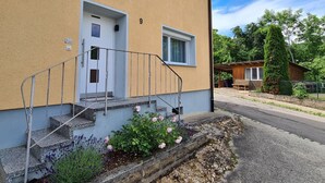 Ein Gebäude mit gelber Fassade, einer weißen Tür und einer kleinen Veranda mit Metallgeländer.