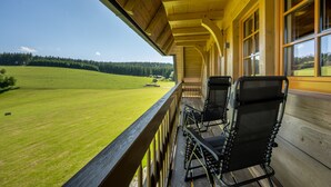 A wooden balcony with two black mesh chairs, overlooking a green field and forest. - Apartment 'Tannenstube' with Mountain View, Balcony and Wi-Fi (Breitnau)