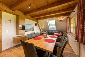 Ein Essbereich mit einem Holztisch, roten Tischsets und einer Sitzbank.