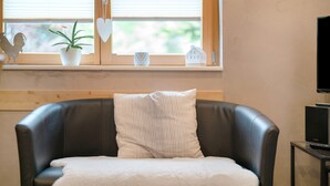 A black leather chair with a white pillow and a white throw blanket.