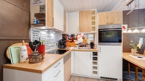 A modern kitchen with white cabinets, a built-in oven, and a coffee machine.