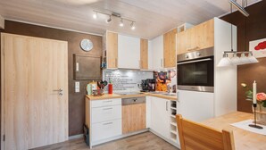 A modern kitchen with wooden cabinets, a dishwasher, a stove, and a clock on the wall.
