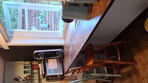 A room with a wooden ceiling, a small kitchenette with a microwave, a dining table with chairs, and a window with a view of greenery. - Tiny house in the Wingster Forest, near Nordesse, peace & relaxation in nature (Wingst)