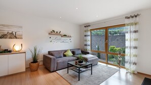 A modern living room with a sofa, coffee table, and a large window with curtains.