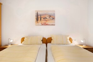 A double bed with two bedside tables, each with a lamp, and a painting on the wall.