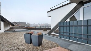 A modern building with a sloped roof, a metal fence, and two large planters with plants. - Studio 'Nr 8' with Balcony and Wi-Fi (Ühlingen-Birkendorf)