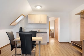 A compact kitchen with a dining area, wooden flooring, and a small seating area.