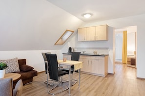 A modern apartment with a dining area, kitchenette, and a bedroom.