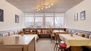 A dining area with tables and chairs, a bench, and a view through large windows. - Apartment '2-zimmer- Nr 7' with Balcony and Wi-Fi (Ühlingen-Birkendorf)