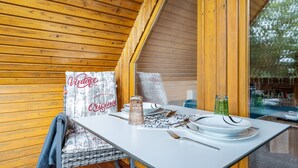 A wooden interior with a table set for dining, a vintage sign, and a view through a window. - Apartment 'Lütt Stuv' with Private Terrace, Shared Garden, and Wi-Fi (Fockbek)