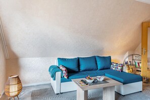 Een moderne woonkamer met een modulaire bank, een salontafel, een lamp en een boekenkast.