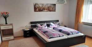 A bedroom with a bed, bedside tables, a nightstand, a vase with flowers, a painting on the wall, and a window with curtains. - Apartment 'Broni' with Private Terrace and Wi-Fi (Prem)