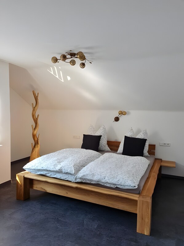 Un dormitorio con cama de madera, una lámpara de pared y una escultura de madera.