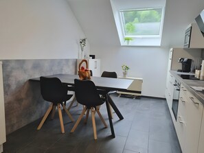Una cocina moderna con una mesa de comedor, sillas y un ventanal.