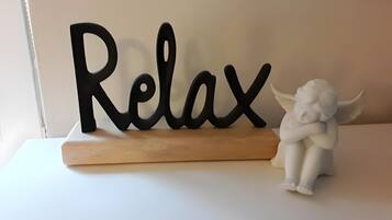 A decorative sign with the word 'Relax' on a wooden base, accompanied by a white angel figurine.