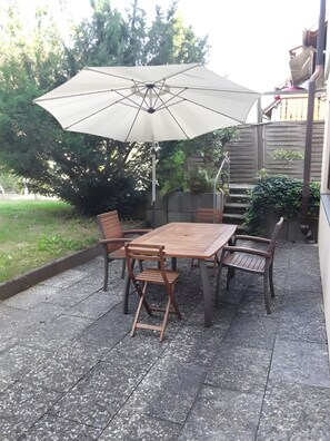 Une terrasse avec une table et des chaises en bois, un parasol et une clôture en bois.