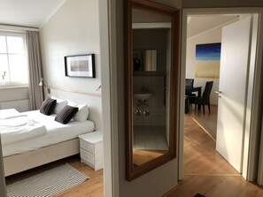 A bedroom with a bed, bedside table, and a mirror.