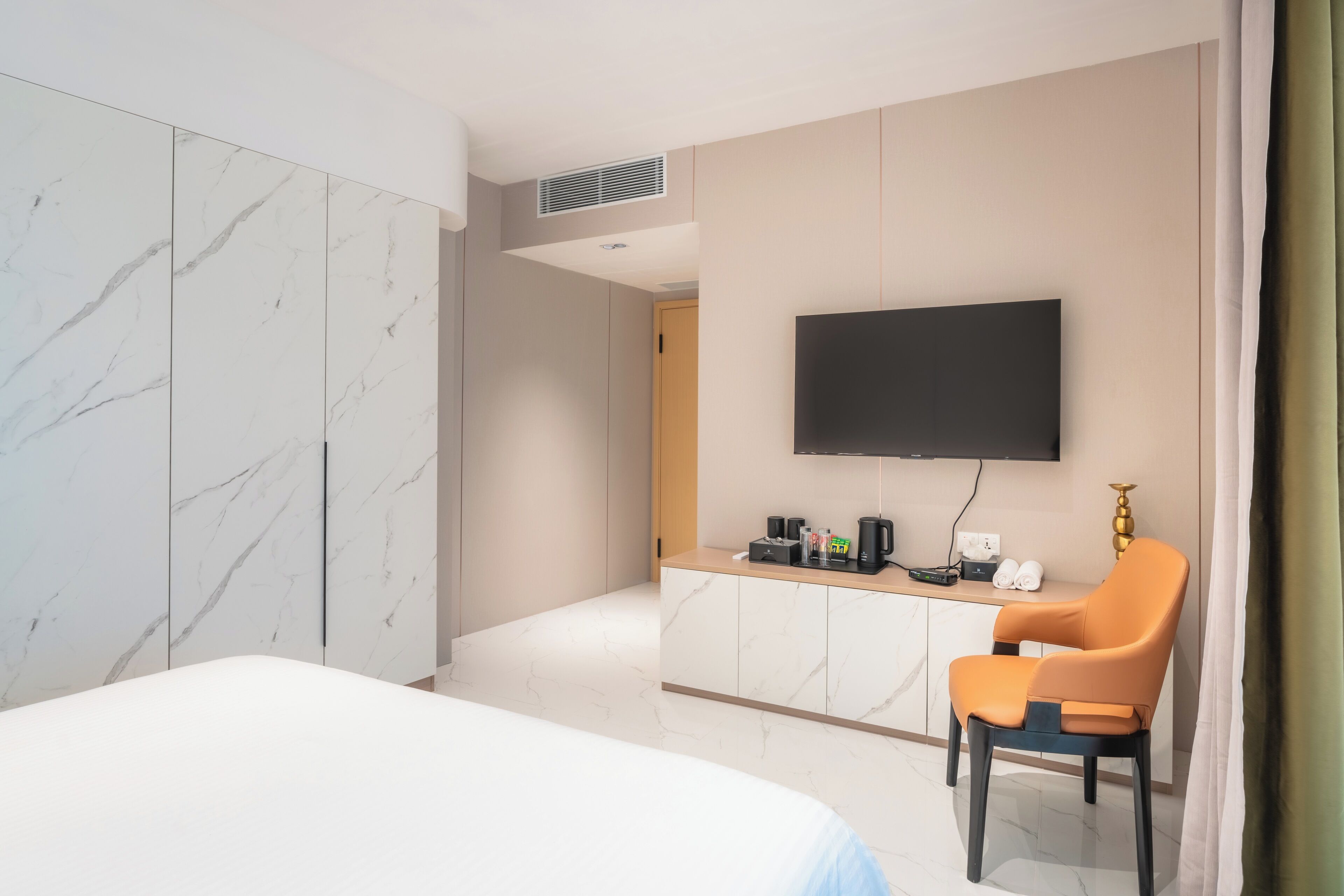 A hotel room with a bed, a desk with a flat-screen TV, a coffee maker, and a chair.