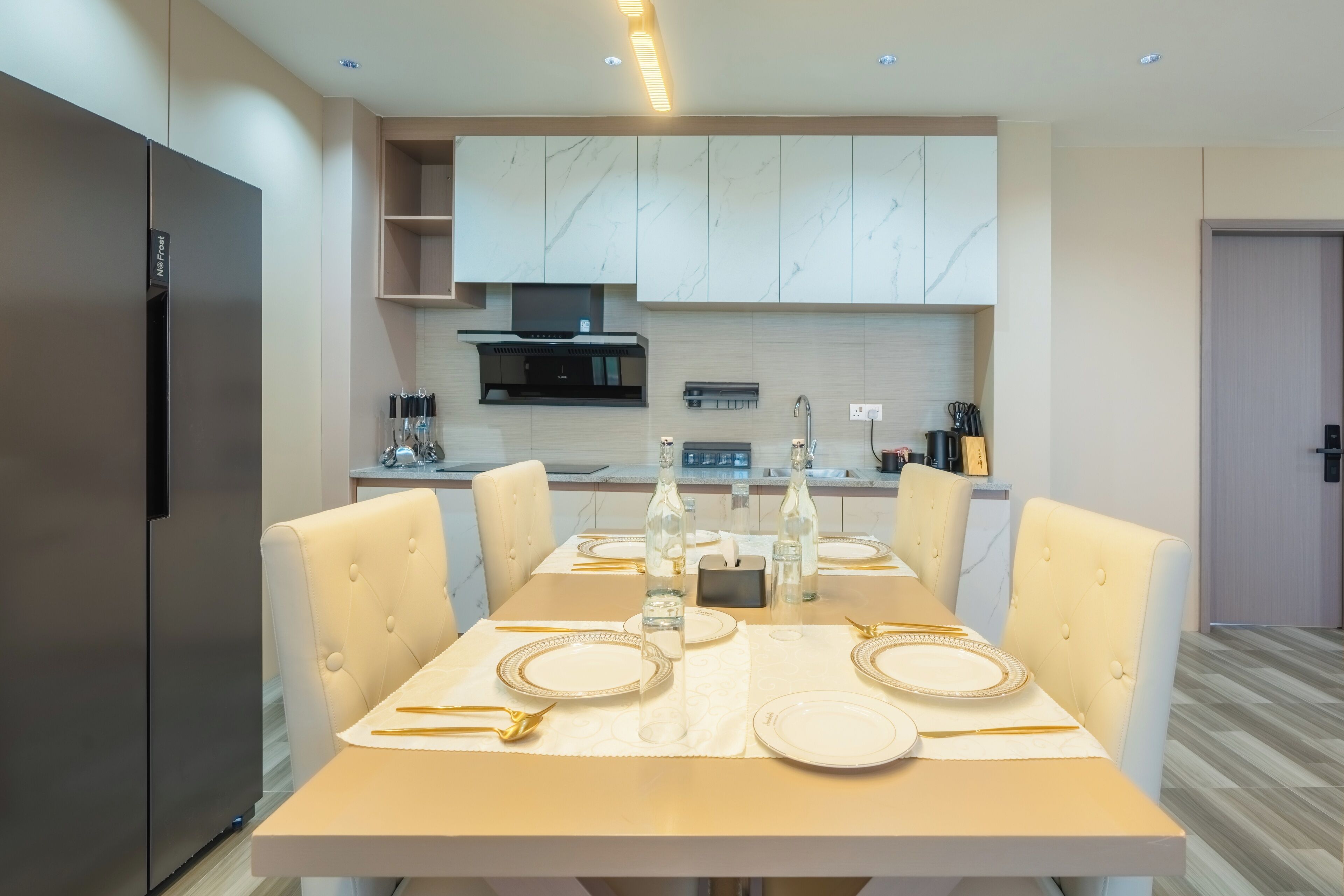 Een moderne keuken met een eettafel voor vier personen, voorzien van een roestvrijstalen koelkast, marmeren kastjes en een inbouwmagnetron.