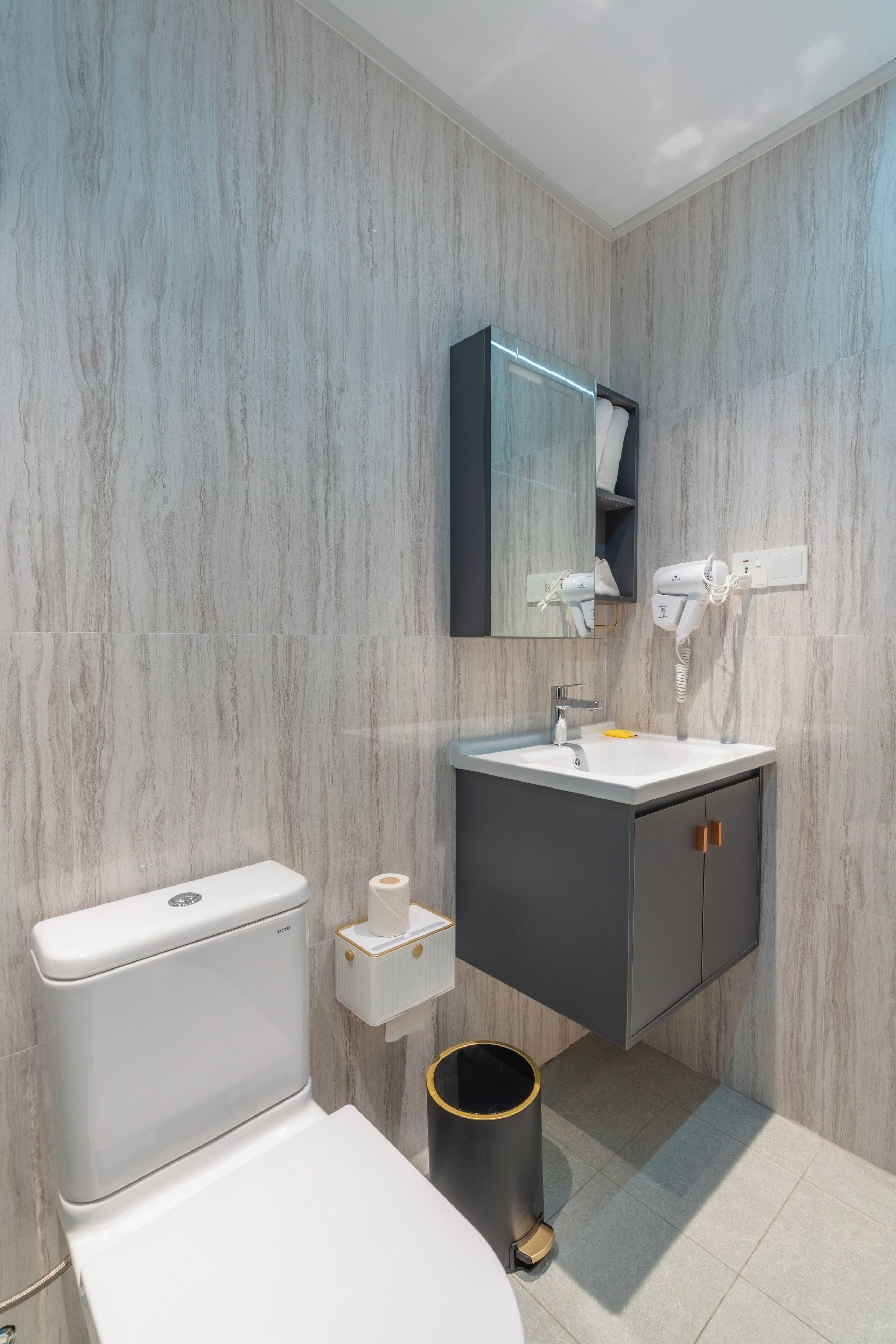 A modern bathroom with a toilet, sink, and mirror.