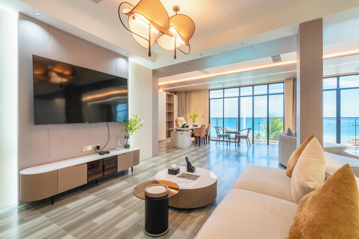A modern living room with a large TV, a round coffee table, and a sofa with cushions.