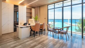 Quarto de hotel moderno com uma escrivaninha, cadeiras e vista para o oceano.