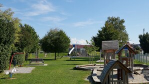 A playground with swings, a slide, and a small wooden structure. - Holiday Apartment 'A' with Balcony and Wi-Fi (Langenargen)