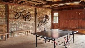 A ping pong table in a room with brick walls, wooden beams, and two bicycles mounted on the wall. - Holiday Apartment 'A' with Balcony and Wi-Fi (Langenargen)
